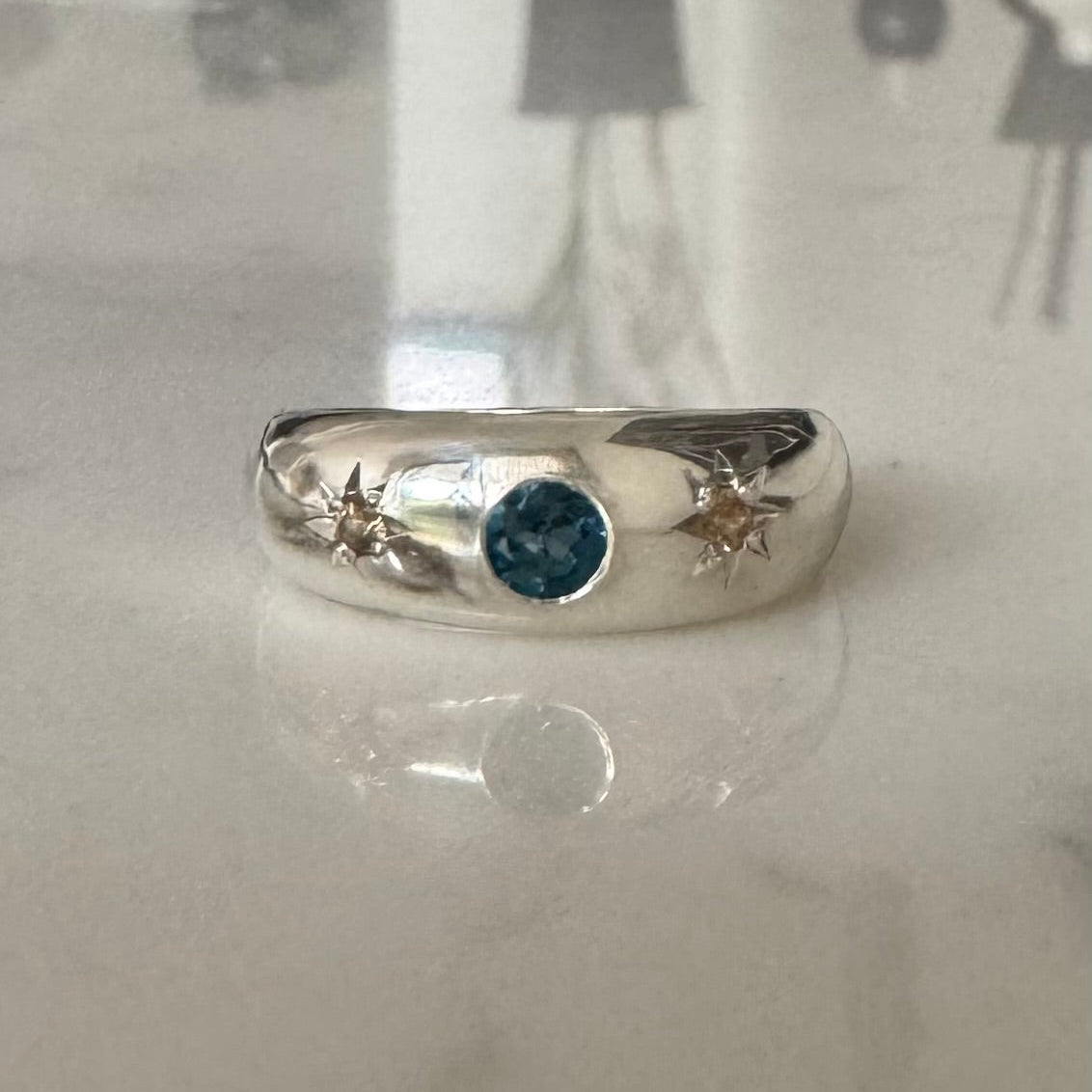 Silver dome ring with flush set topaz and two star set yellow sapphires.
