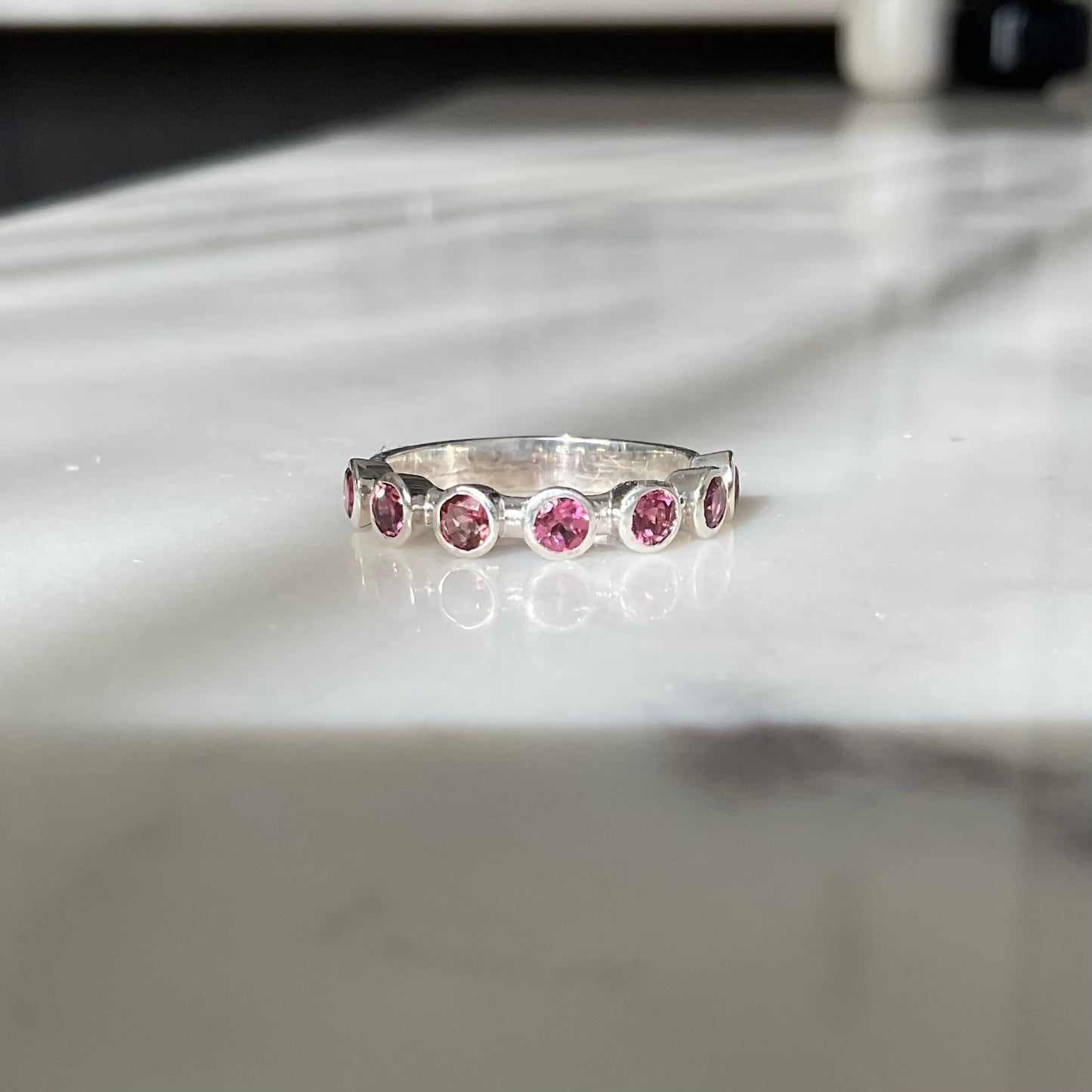 Seven pink tourmaline set around half a ring band.