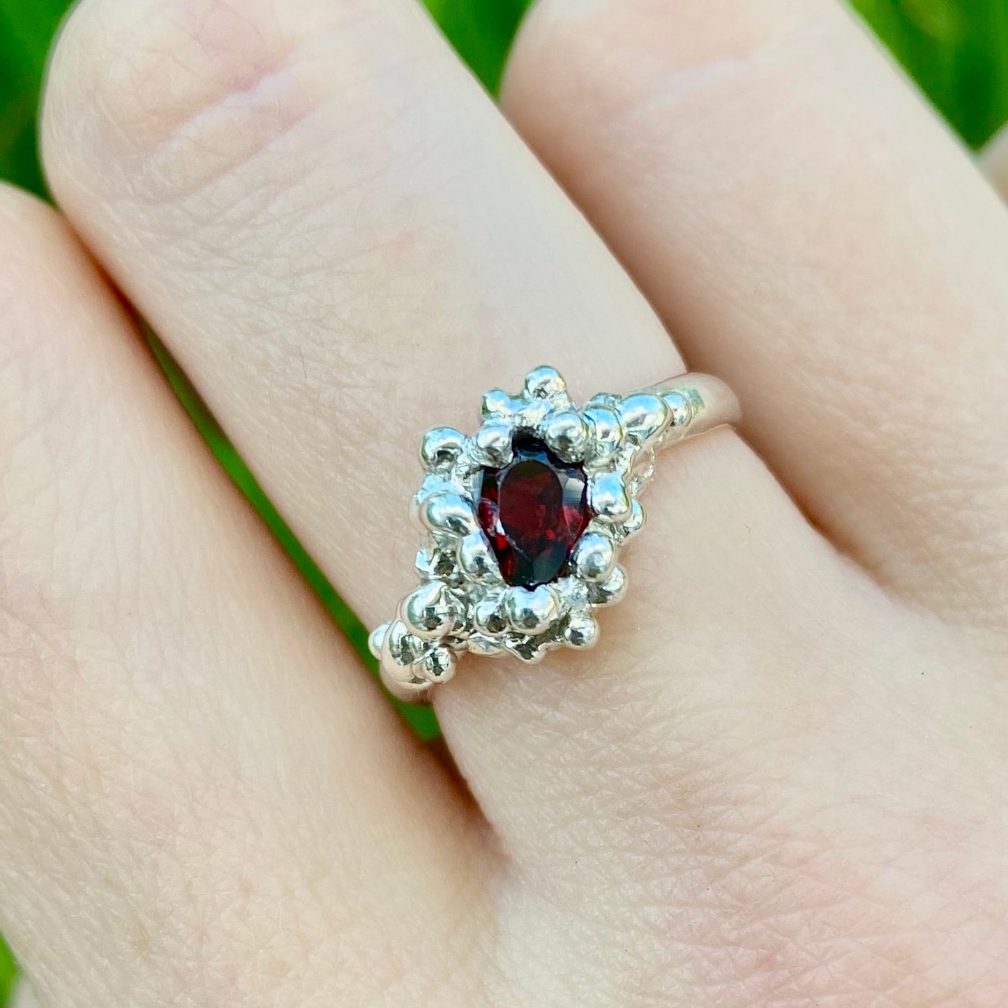 Silver pear shaped garnet ring on model