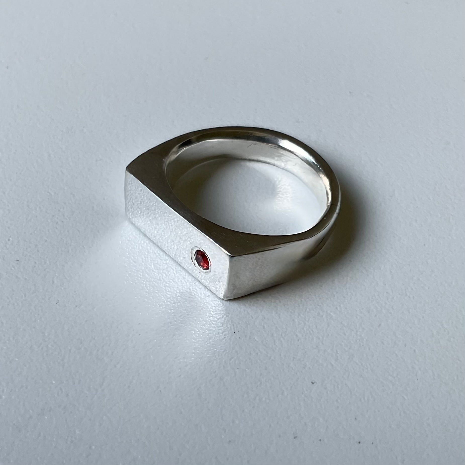 Silver ring with a red gemstone on a gray background