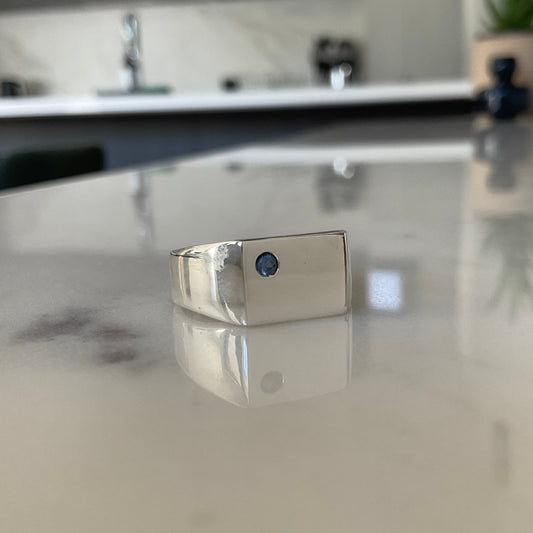 Silver signet ring flush set with a 2.5mm blue sapphire