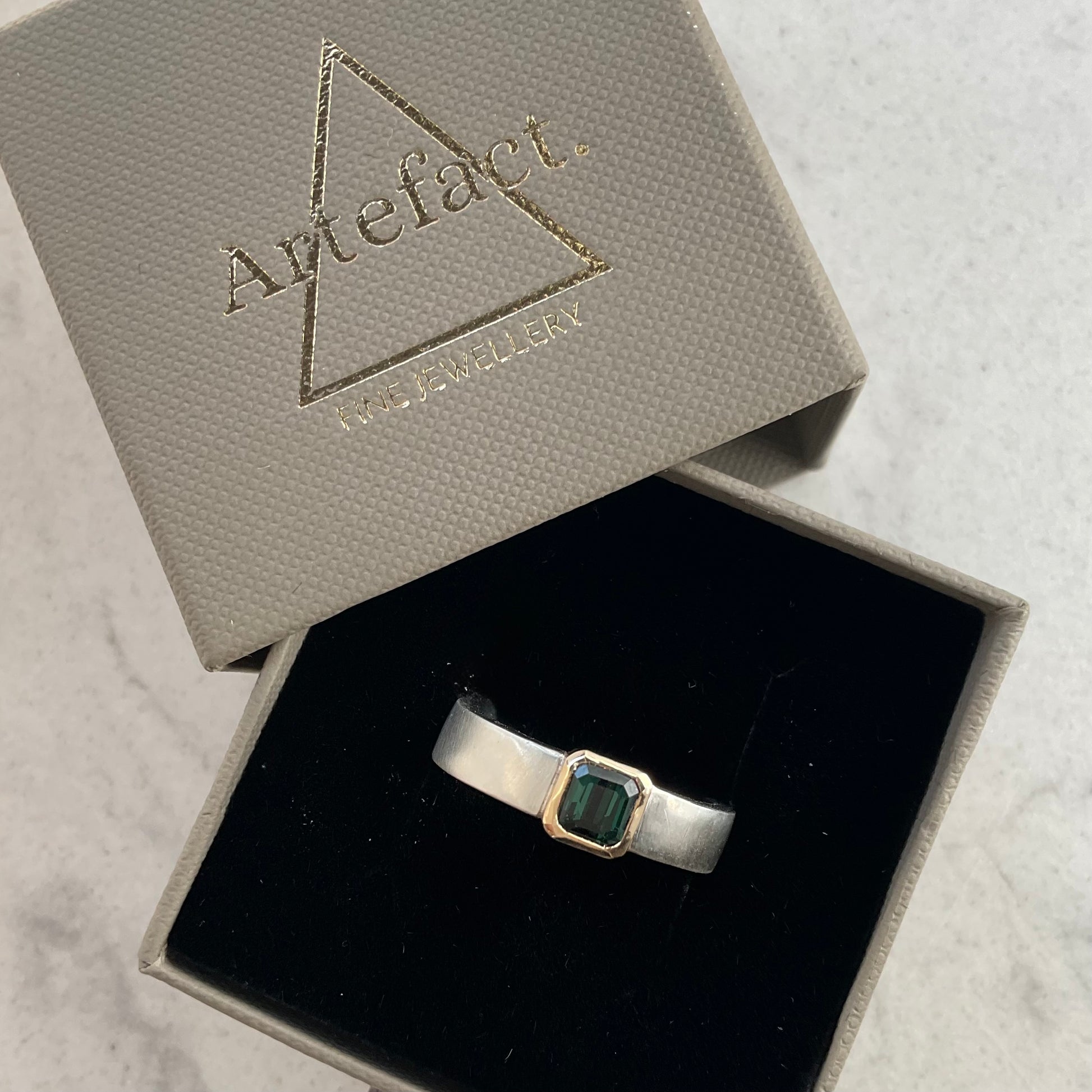 Green tourmaline gemstone set in a 9ct solid gold setting in a brushed silver ring band in an Artefact Fine Jewellery ring box.
