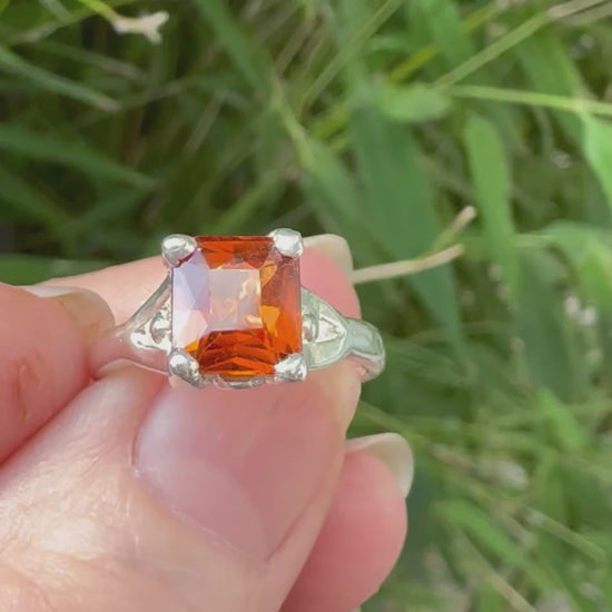 Video of orange garnet solitaire ring shown in hand.