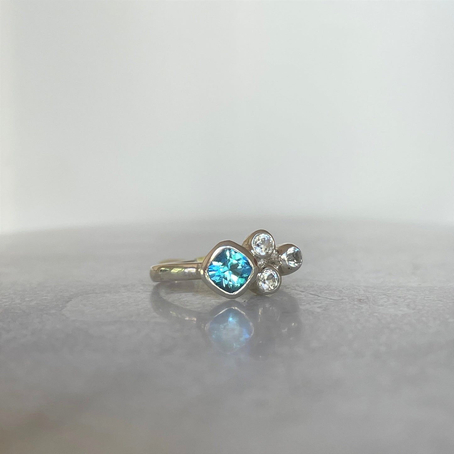 Cushion cut swiss topaz bezel set in cluster ring